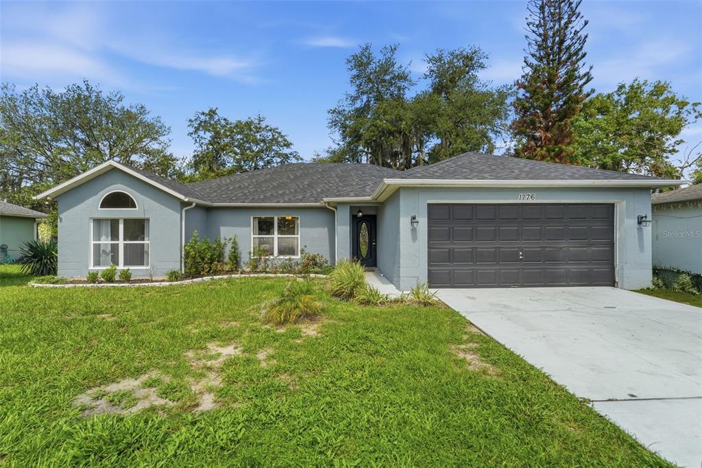 A single-story house with a gray exterior, a two-car garage, and a front lawn — 1176 LYRIC DRIVE, DELTONA, FL