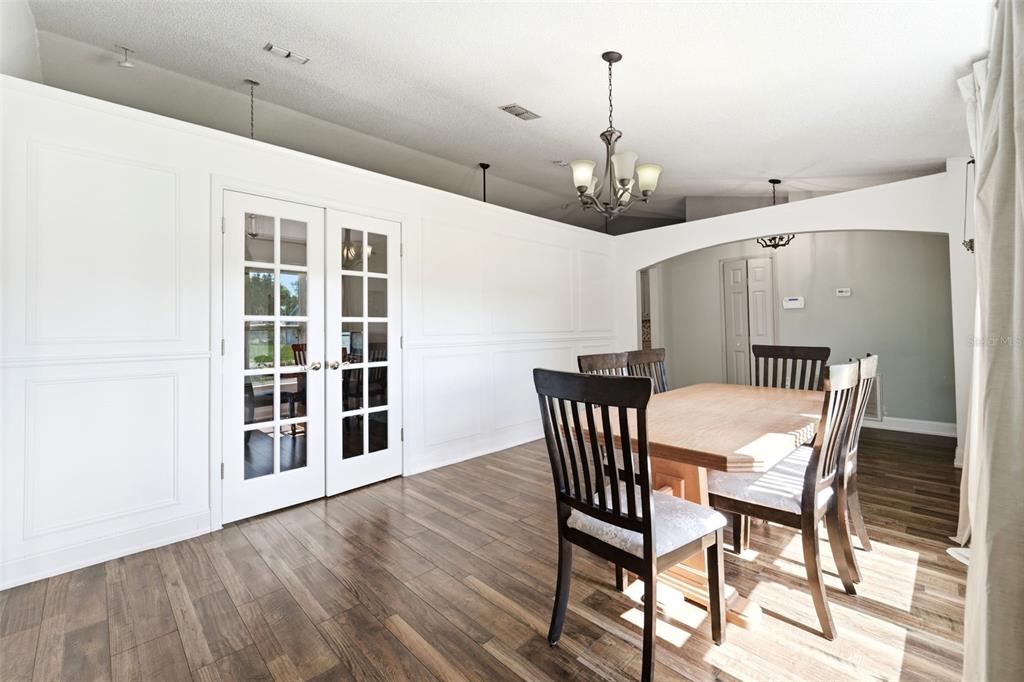 A dining room with wood-look flooring, a wooden table, chairs, and white paneled walls — 1176 LYRIC DRIVE, DELTONA, FL