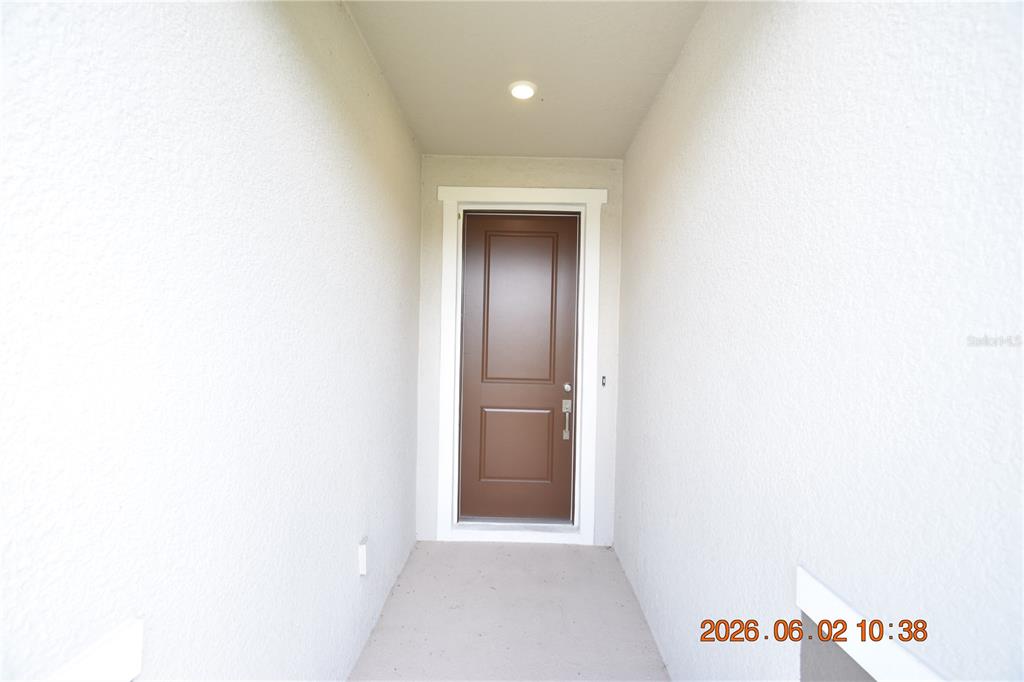 A brown front door is centered at the end of a narrow, covered entryway — 20076 AZUL MARBLE LOOP, LAND O LAKES, FL