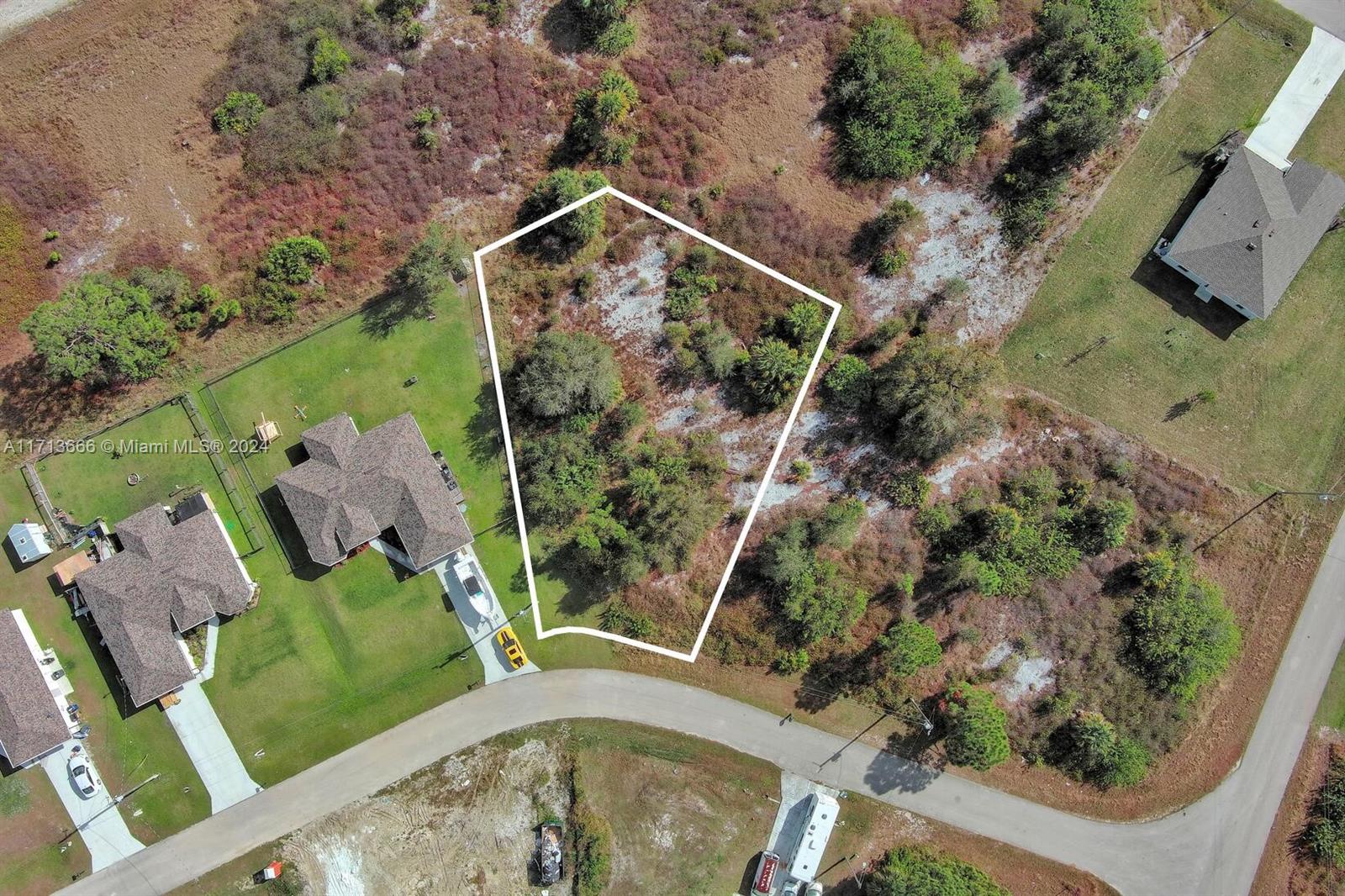 An aerial view shows a vacant, irregularly shaped residential lot outlined in white — 309 Raber Ave, Lehigh Acres FL 33974, LEHIGH ACRES, FL