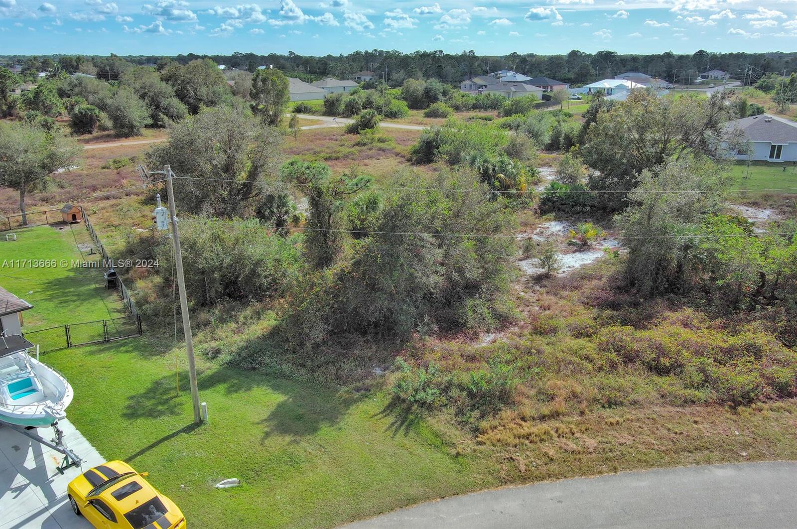 An aerial view shows a vacant, overgrown residential lot next to a house with a boat — 309 Raber Ave, Lehigh Acres FL 33974, LEHIGH ACRES, FL