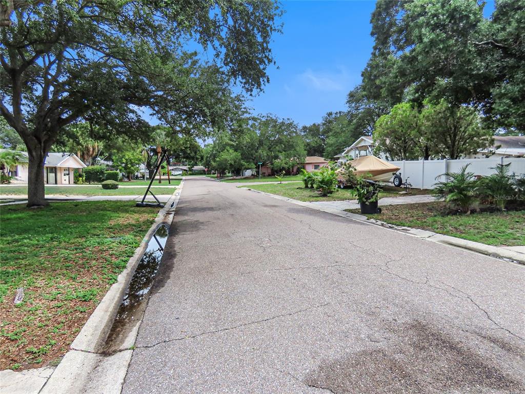A residential street with a basketball hoop, a boat on a trailer, and mature trees — 2434 65TH STREET N, ST PETERSBURG, FL