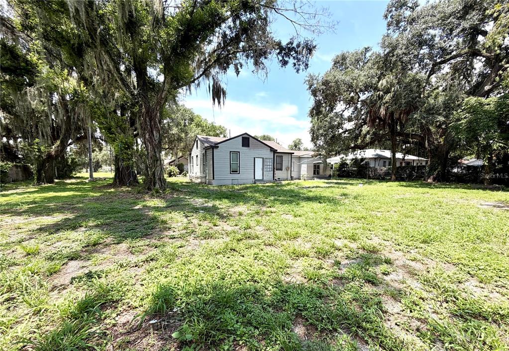 A light-colored house with a gabled roof sits on a large, grassy lot — 629 AVENUE A NE, WINTER HAVEN, FL