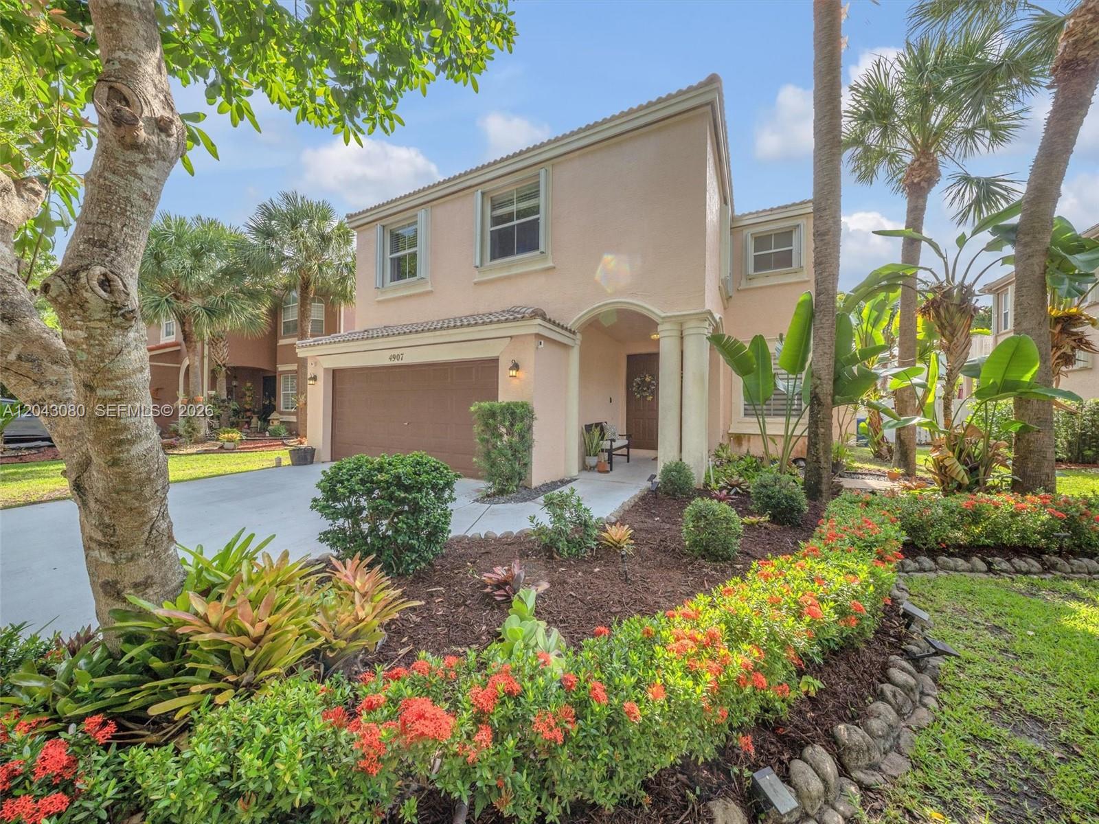 A two-story peach-colored house features a brown garage, a covered entryway, and landscaped front gardens — 4907 SW 166th Ave, Miramar FL 33027, MIRAMAR, FL