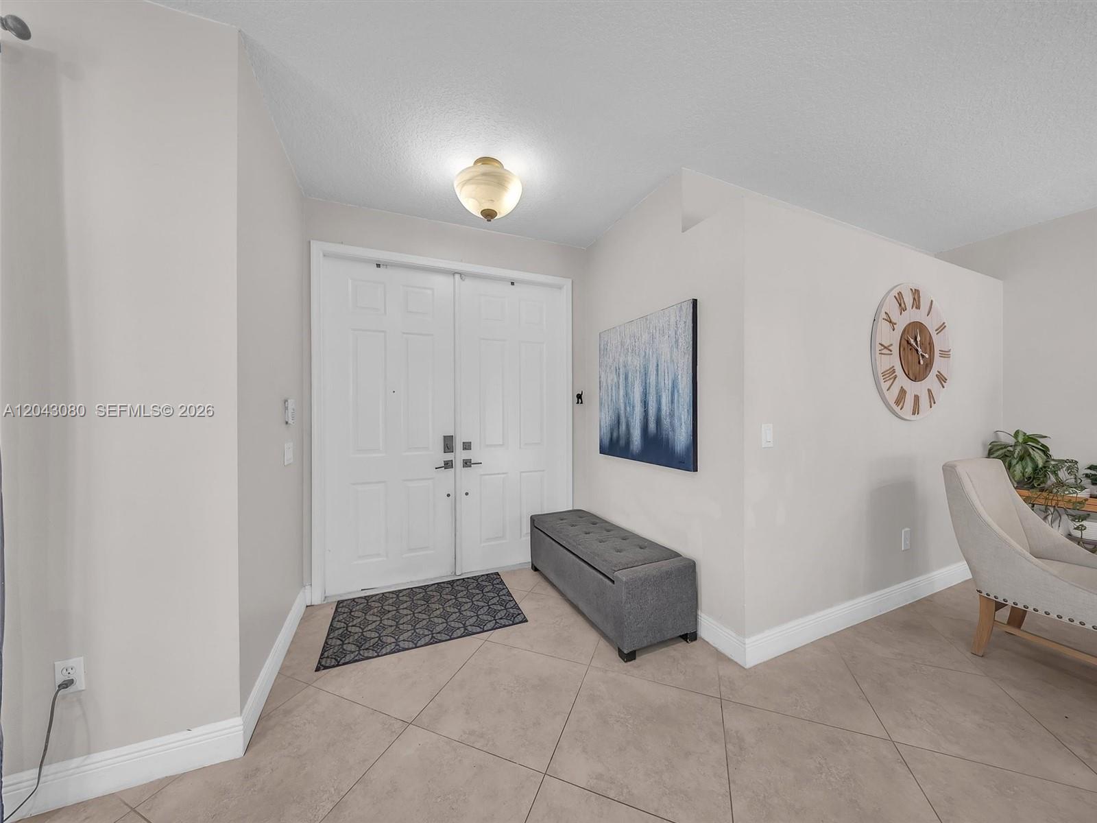 An entryway features double white doors, a gray storage bench, and a large wall clock — 4907 SW 166th Ave, Miramar FL 33027, MIRAMAR, FL