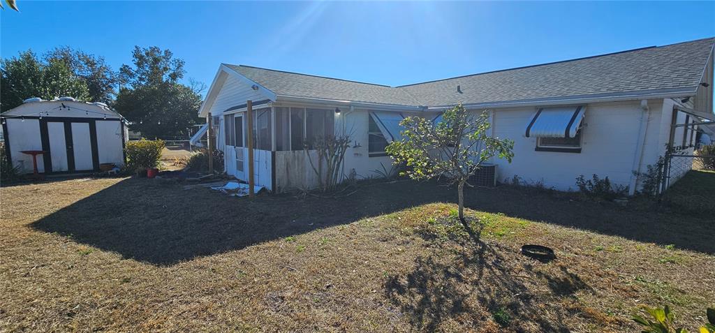 A white house with a screened-in porch, metal window awnings, and a detached storage shed — 6020 17TH STREET, ZEPHYRHILLS, FL