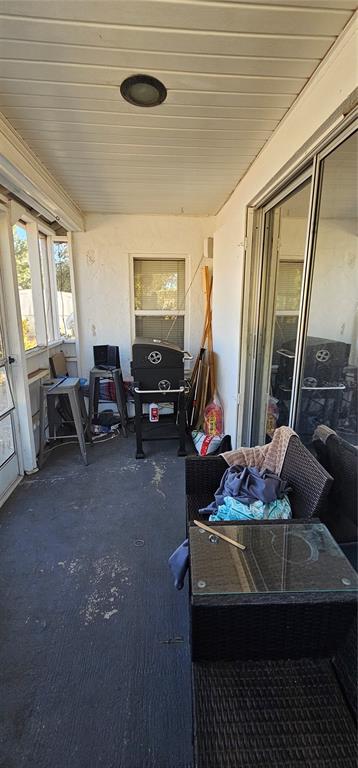 A covered patio features a concrete floor, a grill, and outdoor furniture next to sliding doors — 6020 17TH STREET, ZEPHYRHILLS, FL