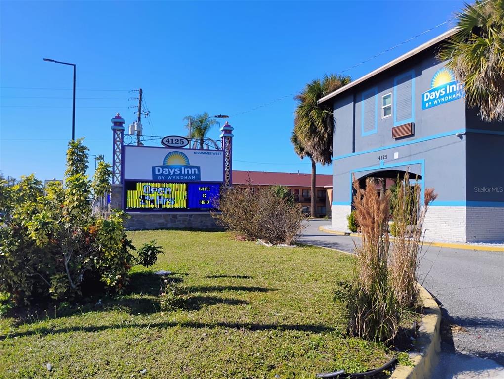 A Days Inn by Wyndham hotel exterior features a prominent digital sign and palm trees — 4125 W VINE STREET, KISSIMMEE, FL