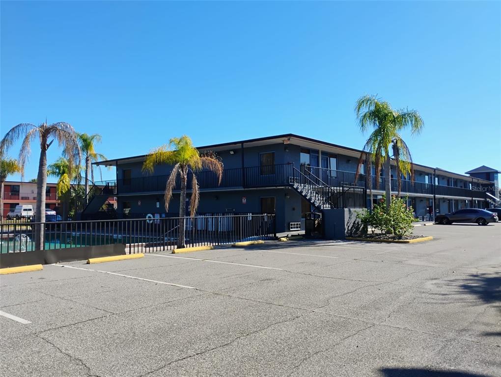 A two-story dark gray apartment building with exterior walkways, palm trees, and a parking lot — 4125 W VINE STREET, KISSIMMEE, FL