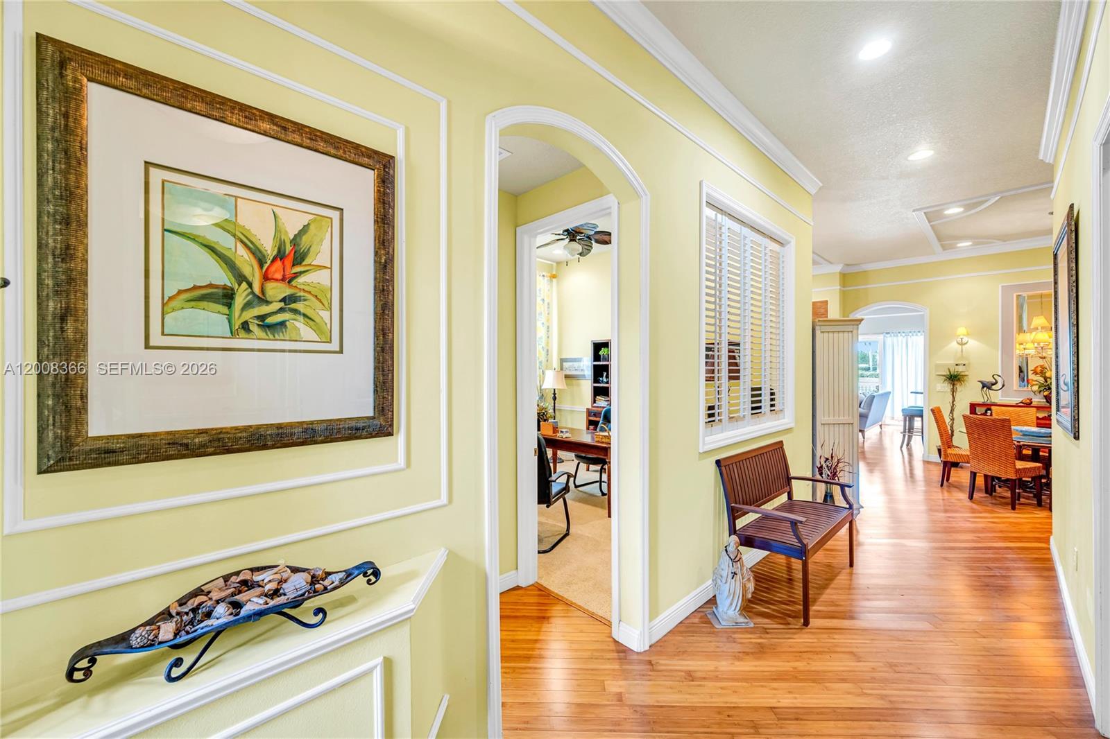 A hallway with yellow walls, hardwood floors, a framed plant print, and an arched doorway — 3465 NE 2nd St, Homestead FL 33033, HOMESTEAD, FL