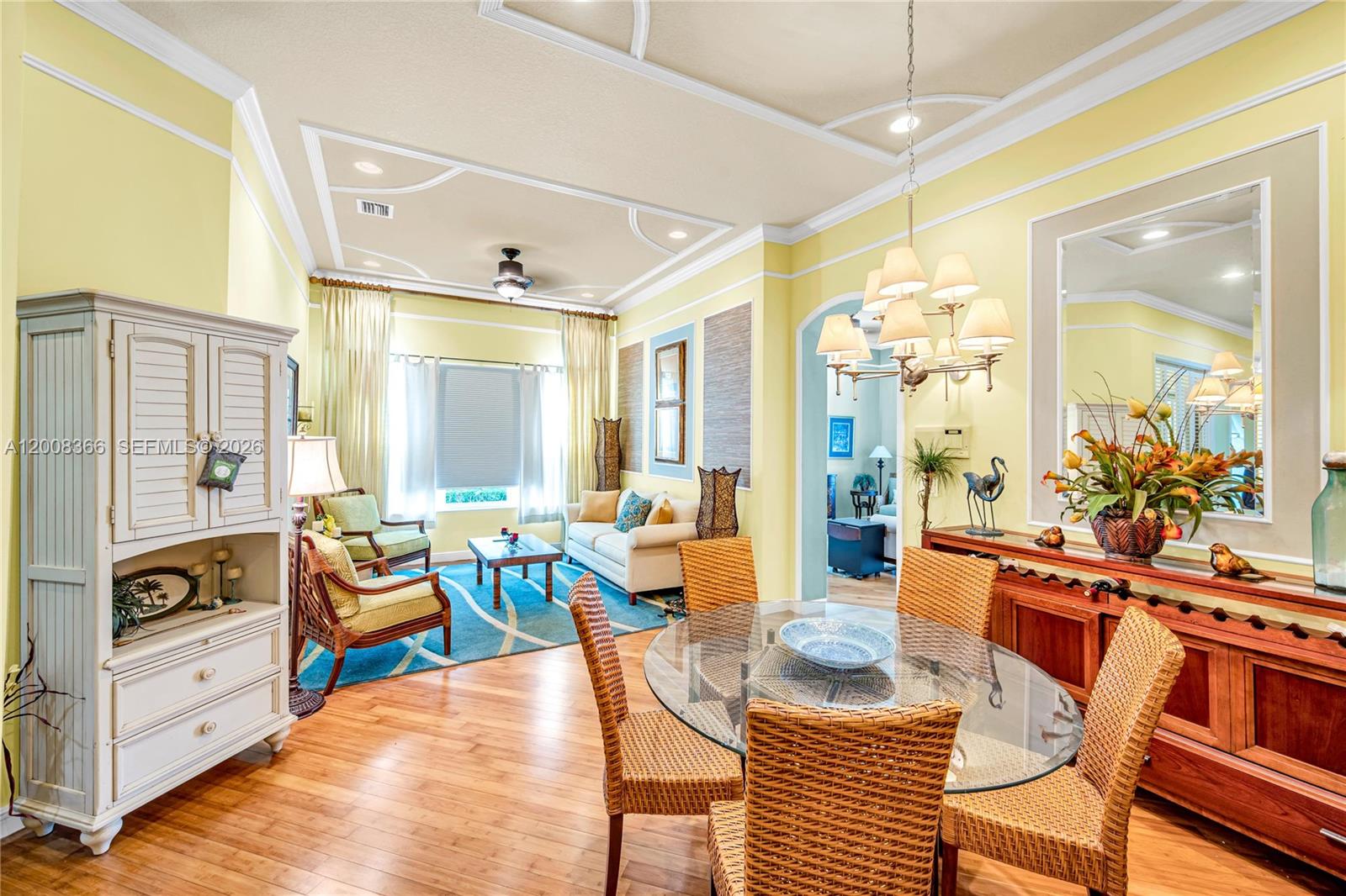 A dining area with a glass table and wicker chairs opens into a yellow living room — 3465 NE 2nd St, Homestead FL 33033, HOMESTEAD, FL