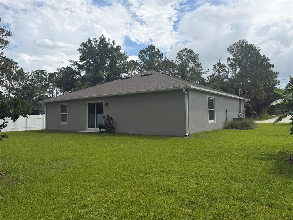 The exterior view shows the gray stucco back of a house with a sliding door — 177 UNDERWOOD TRAIL, PALM COAST, FL