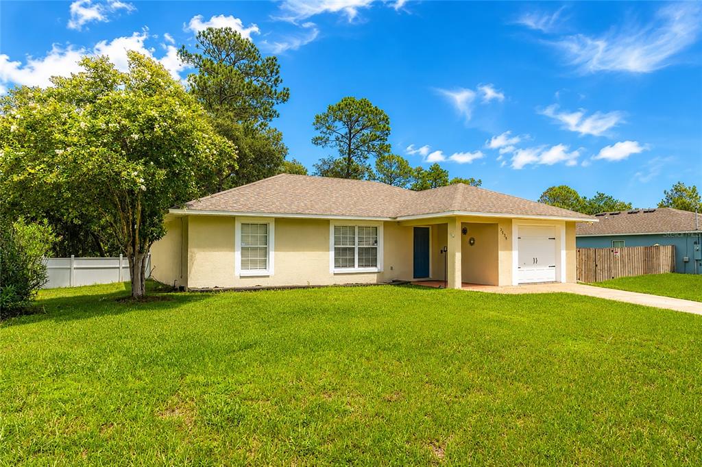 A single-story house with a yellow stucco exterior, a garage, and a large front lawn — 3424 SANBORN LANE, DELTONA, FL