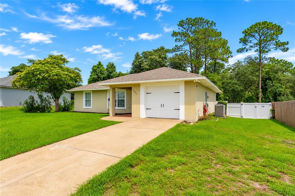 A single-story house with a tan exterior, a white garage door, and a concrete driveway — 3424 SANBORN LANE, DELTONA, FL