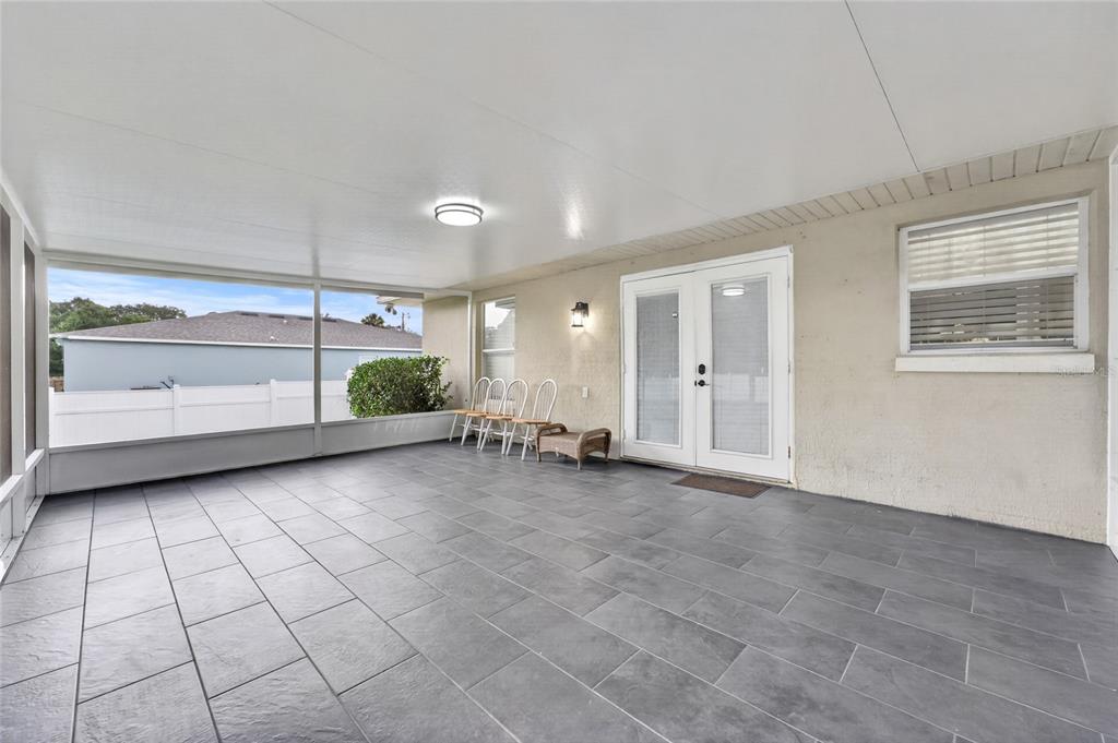 A covered patio features gray tile flooring, white walls, and a screened-in outdoor area — 3424 SANBORN LANE, DELTONA, FL