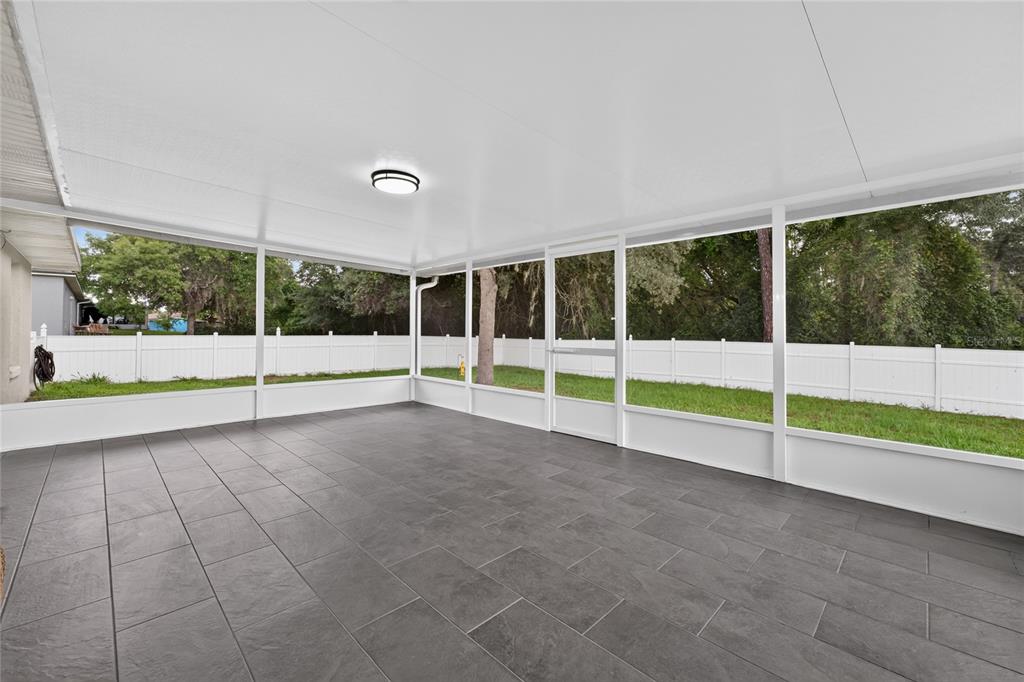 A screened-in patio with dark tile flooring, a white ceiling, and a view of a backyard — 3424 SANBORN LANE, DELTONA, FL