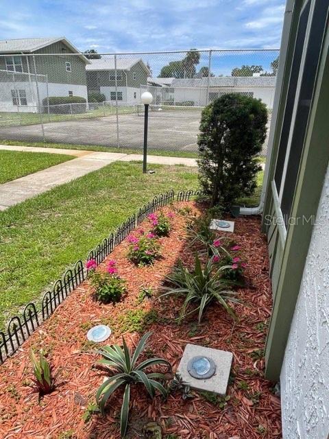 A landscaped garden bed with mulch, small plants, and solar lights sits beside a building — 840 CENTER AVENUE UNIT 67, HOLLY HILL, FL