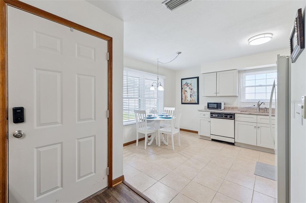 A kitchen and dining area with white cabinets, tile flooring, and a small round table — 840 CENTER AVENUE UNIT 67, HOLLY HILL, FL