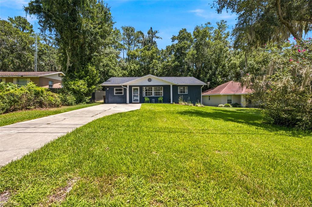 A single-story blue house with a concrete driveway and a large front lawn — 723 SE 30TH AVENUE, OCALA, FL