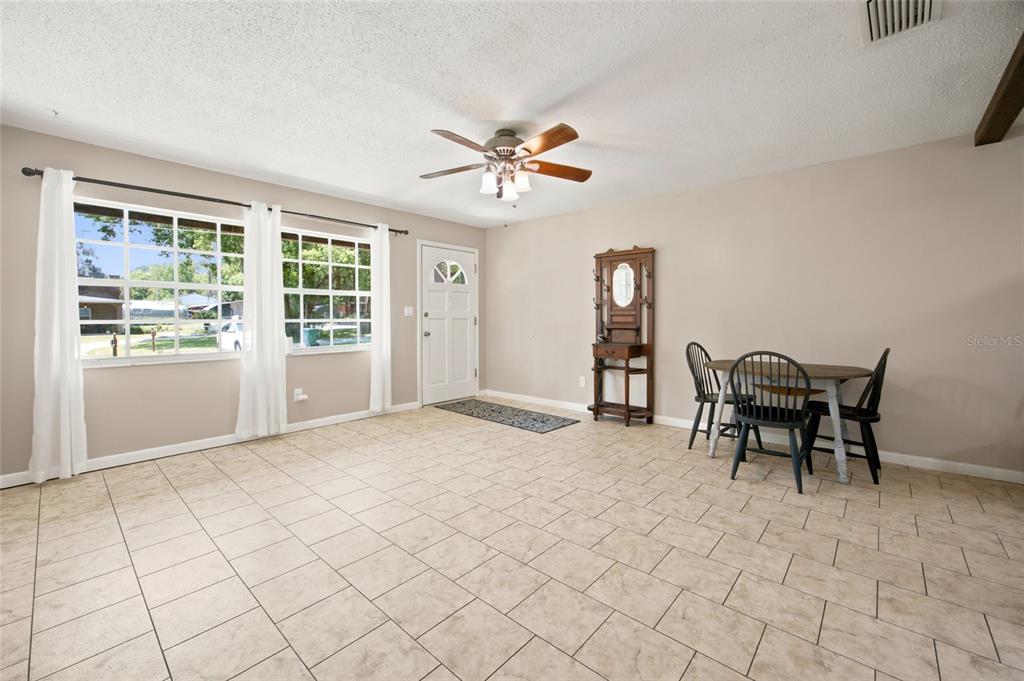 A dining area with tile flooring, a ceiling fan, and a wooden hutch near windows — 723 SE 30TH AVENUE, OCALA, FL