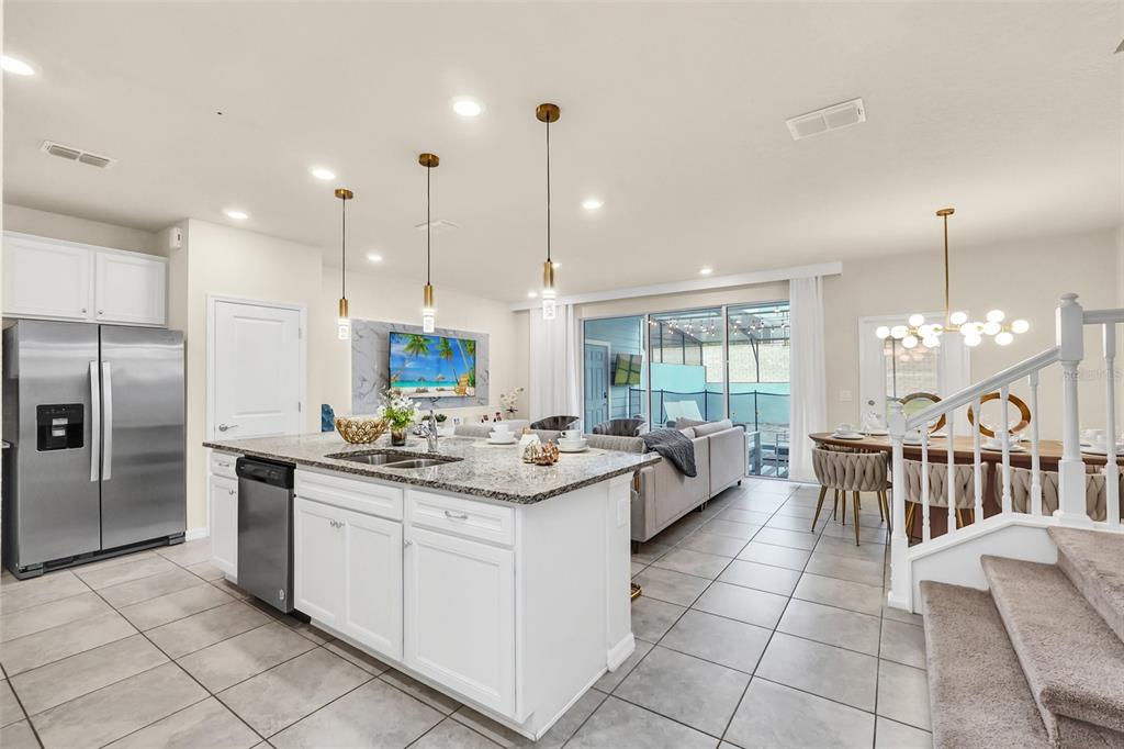 A modern open-concept kitchen and living area with white cabinets, granite countertops, and tile flooring — 830 PARADISE DRIVE, DAVENPORT, FL