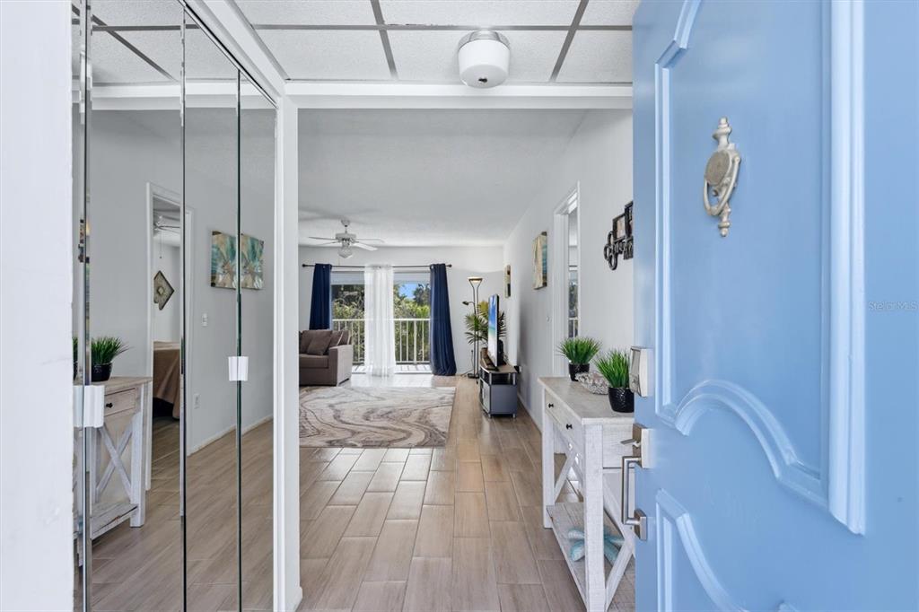 A view through a blue front door into an apartment with wood-look tile flooring — 1714 69TH AVENUE W UNIT A303, BRADENTON, FL