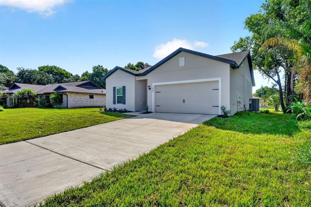 A single-story house with a beige exterior, a two-car garage, and a concrete driveway — 1669 MONTAGUE STREET, DELTONA, FL