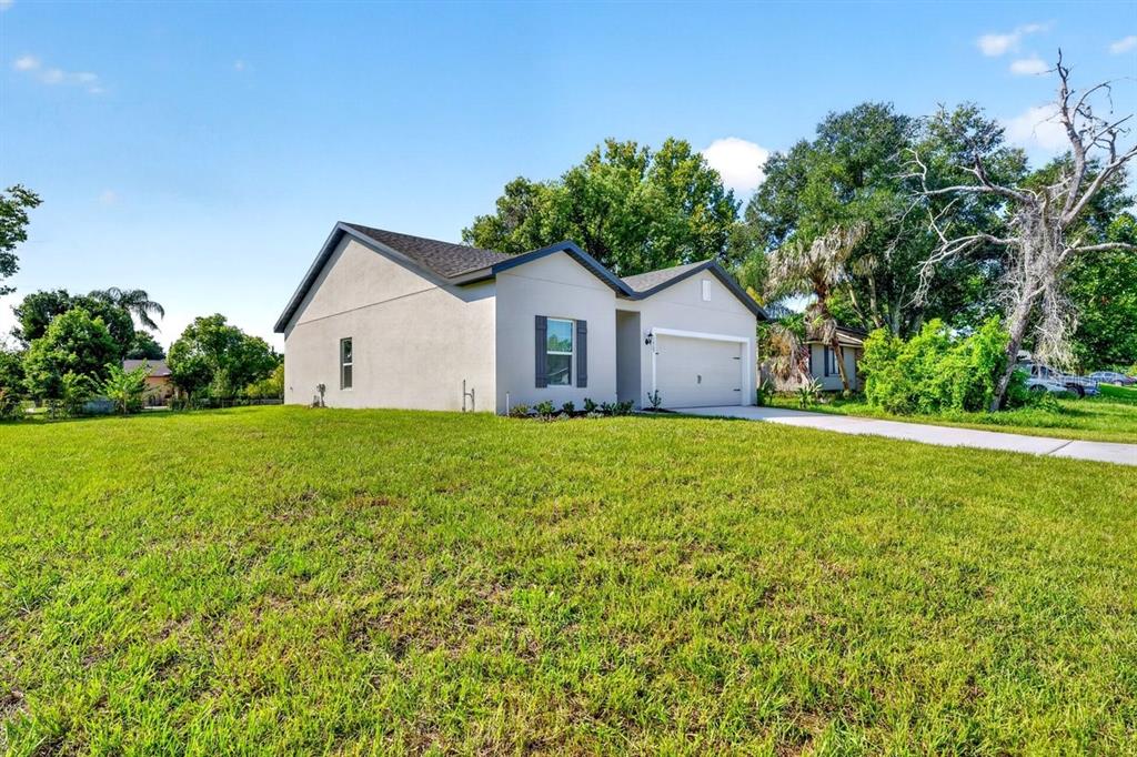 A single-story house with a light-colored exterior, a garage, and a large front lawn — 1669 MONTAGUE STREET, DELTONA, FL