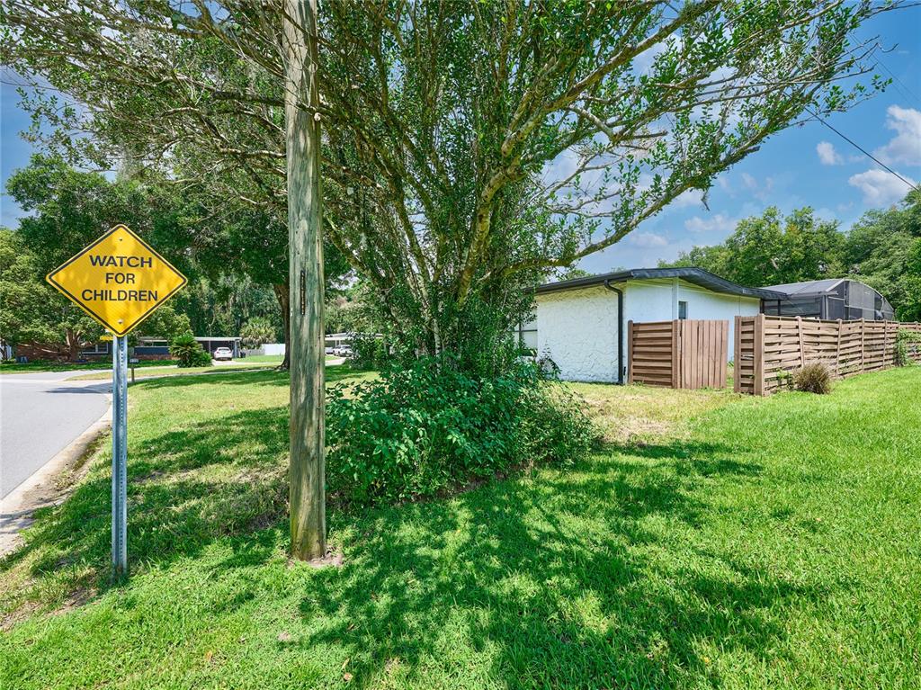 A yellow road sign reading "Watch for Children" stands on a grassy lawn near a house — 1100 CORNELL DRIVE, SANFORD, FL