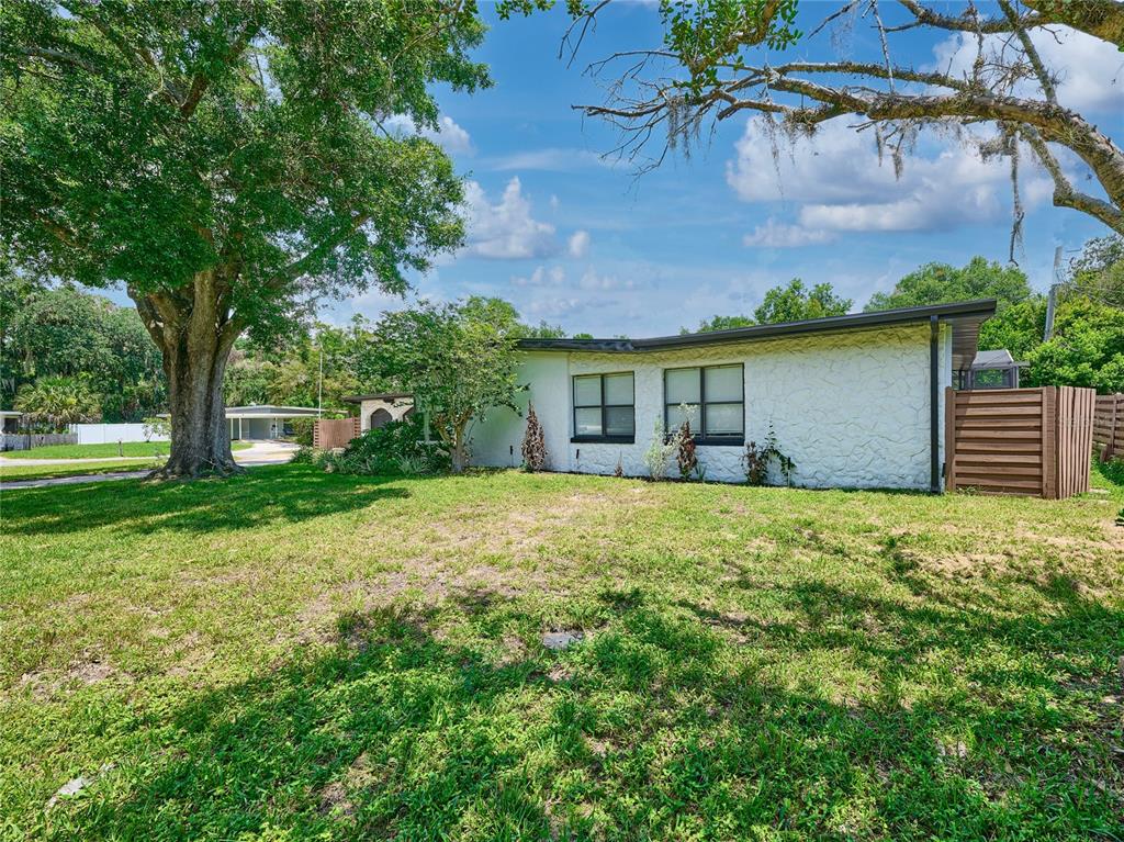 A white, single-story house with a textured exterior and two windows sits on a lawn — 1100 CORNELL DRIVE, SANFORD, FL