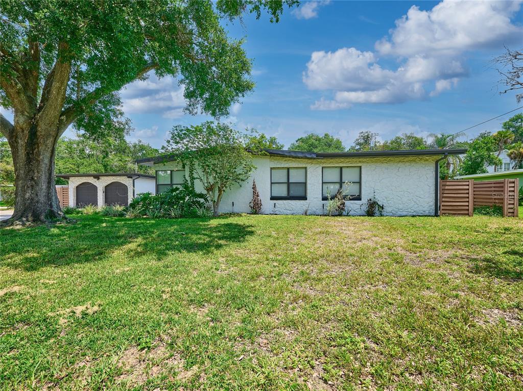A white, single-story house with a flat roof and a large tree in the yard — 1100 CORNELL DRIVE, SANFORD, FL