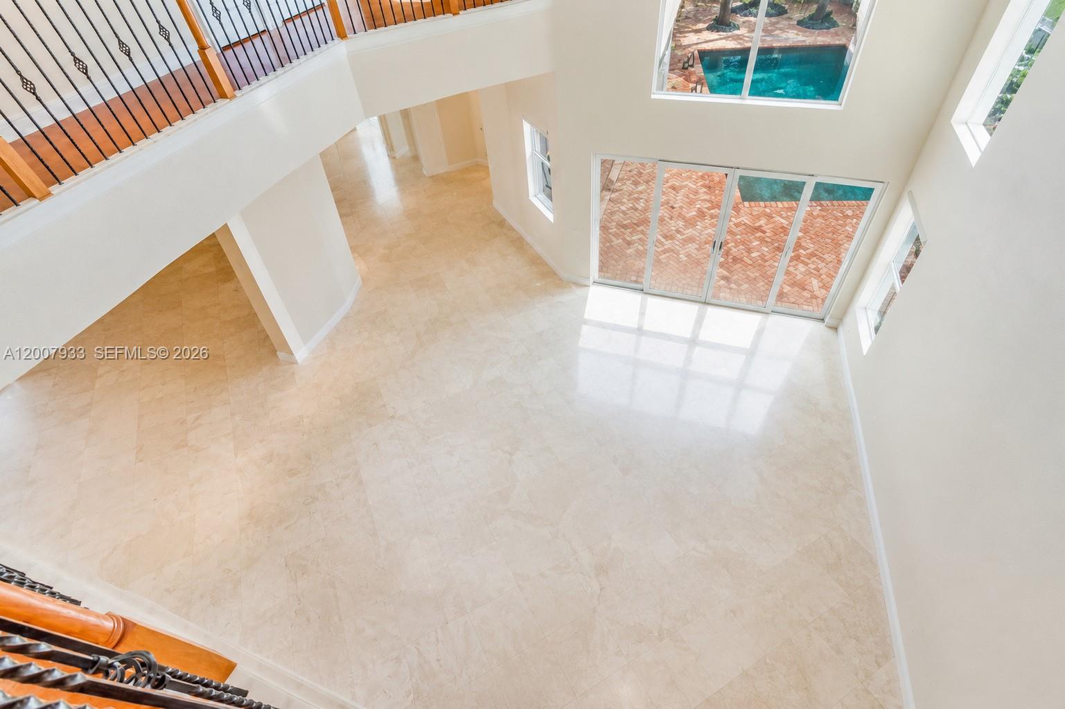 A high-angle view of a two-story living area with tile floors and a pool view — 19471 NE 14th Ct, Miami FL 33179, MIAMI, FL
