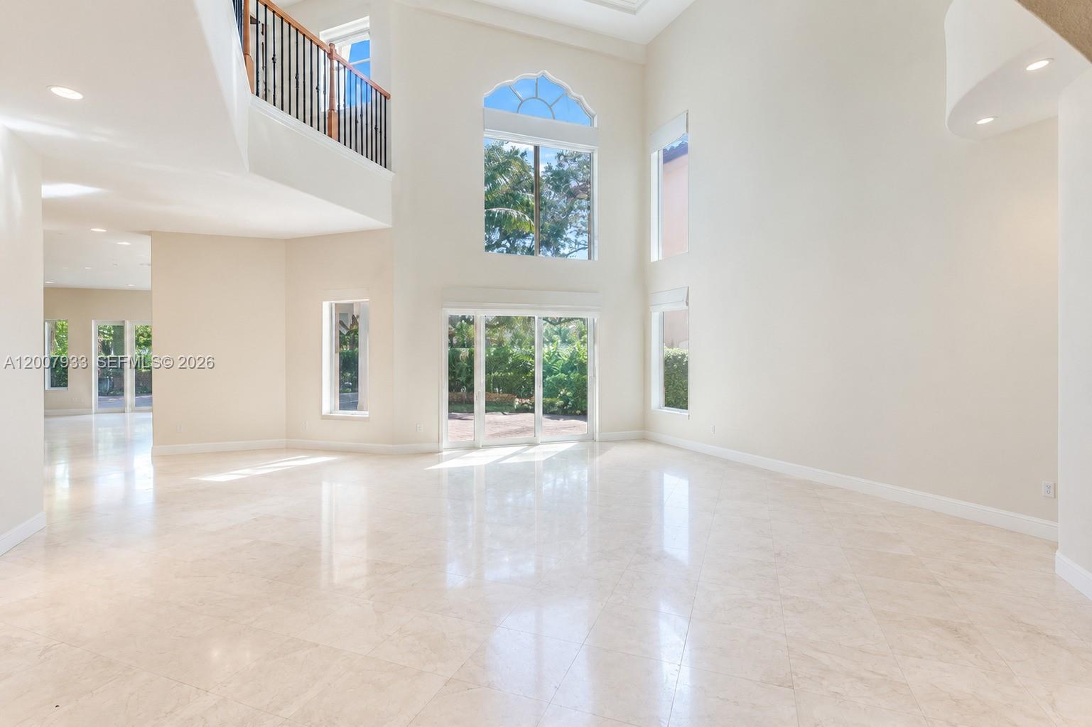 A spacious, high-ceilinged living room features light tile flooring, large windows, and a balcony overlook — 19471 NE 14th Ct, Miami FL 33179, MIAMI, FL