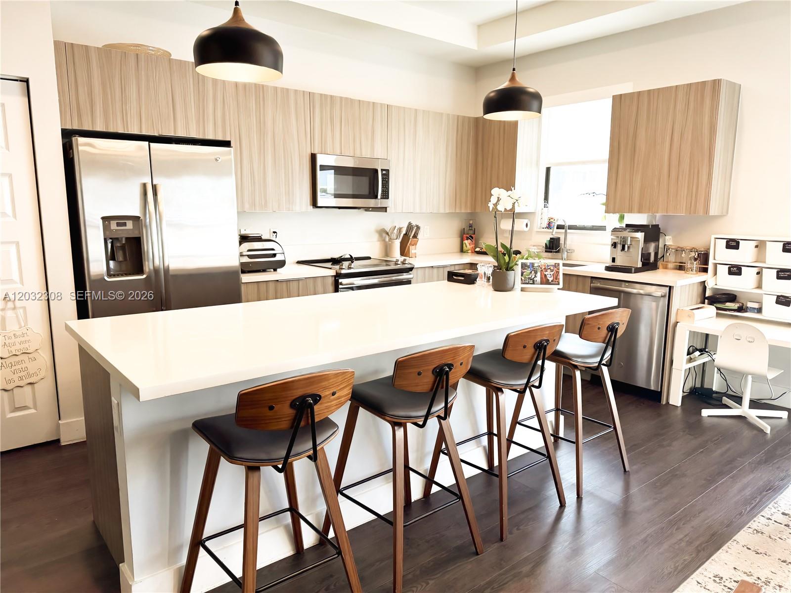 A modern kitchen features a large white island, wood-grain cabinets, and four bar stools — 10455 NW 82nd St # 32, Doral FL 33178, DORAL, FL