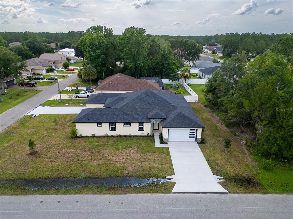 A single-story house with a white garage door, tan stucco walls, and a dark roof — 2 BUTTONBUSH LANE, PALM COAST, FL