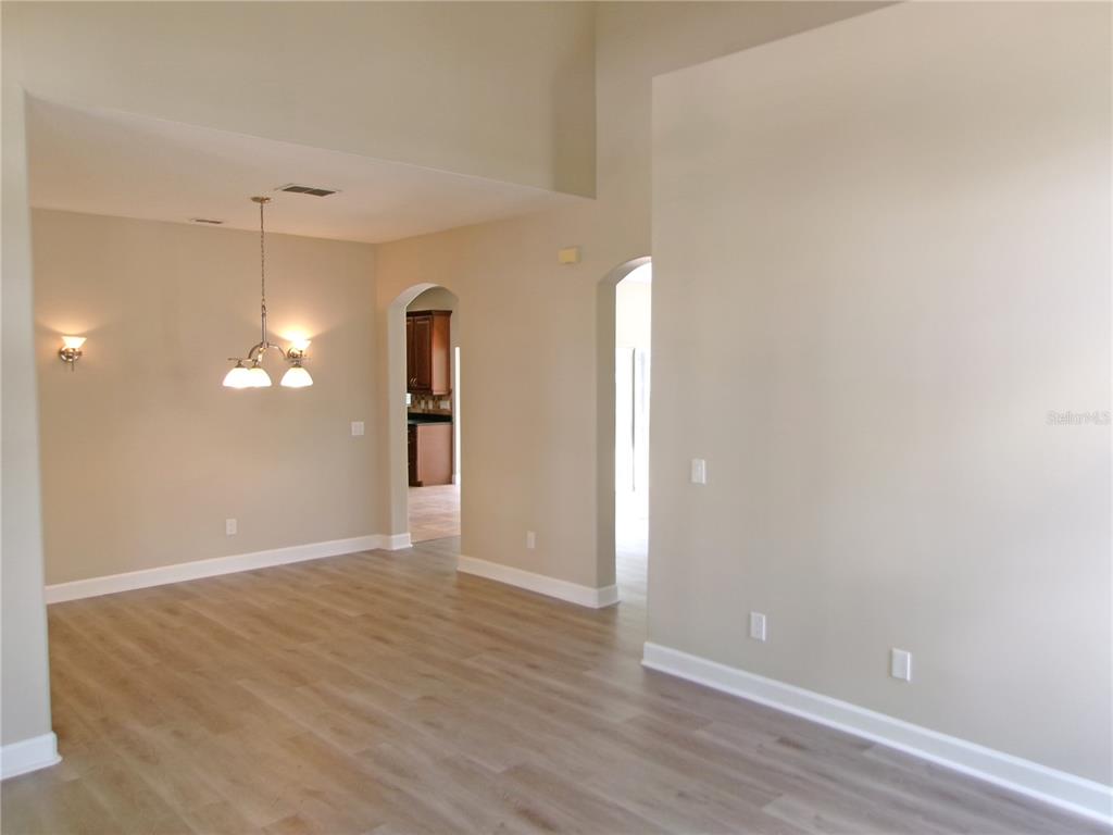 An open-concept room features light-colored walls, wood-look flooring, a vaulted ceiling, and arched doorways — 11314 OYSTER BAY CIRCLE, NEW PORT RICHEY, FL