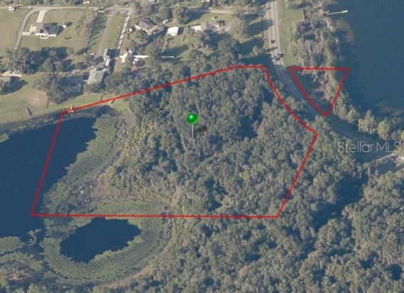An aerial view shows a wooded plot of land outlined in red next to a lake — 2532 E NEW YORK AVENUE, DELAND, FL