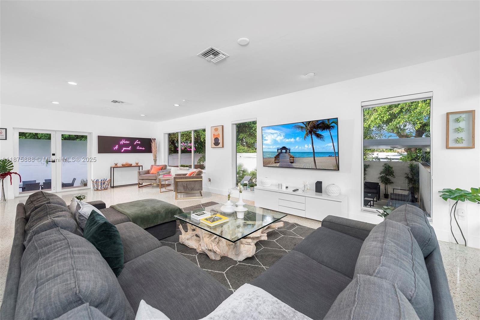 A modern living room features a large grey sectional, glass coffee table, and wall-mounted television — 1019 NE 87th St, Miami FL 33138, MIAMI, FL