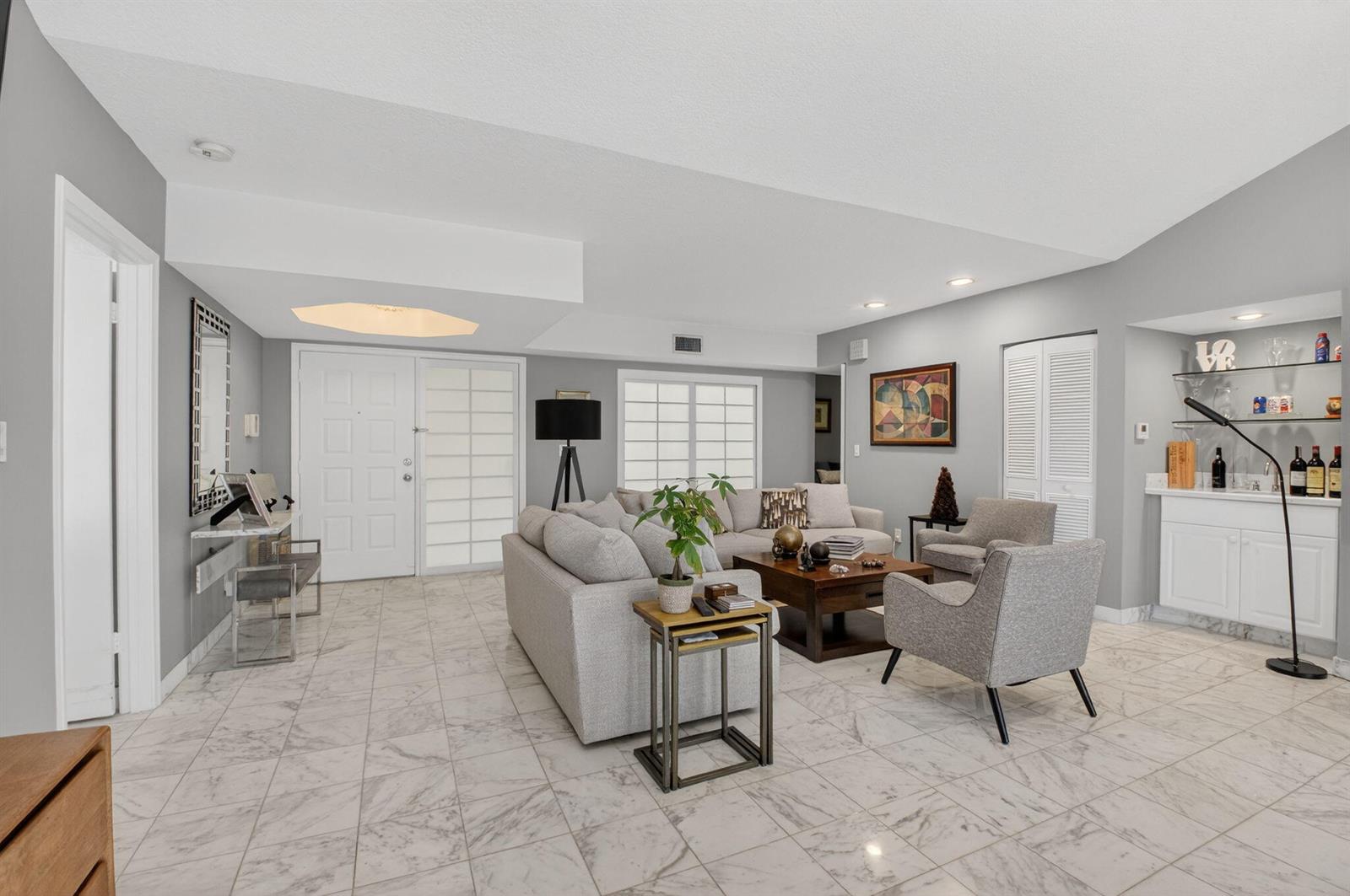 A living room with marble floors, a grey sectional sofa, and a built-in wet bar — 7369 Orangewood Lane # 307, Boca Raton FL 33433, BOCA RATON, FL