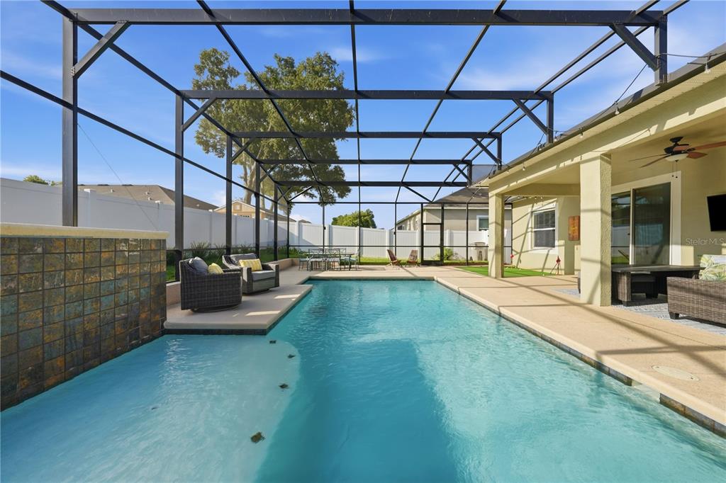 A screened-in swimming pool with a stone water feature and patio furniture — 3629 PELOCK DRIVE, APOPKA, FL