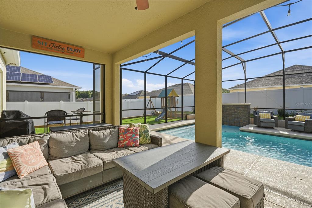A covered patio features outdoor furniture, a swimming pool, and a screened-in backyard area — 3629 PELOCK DRIVE, APOPKA, FL