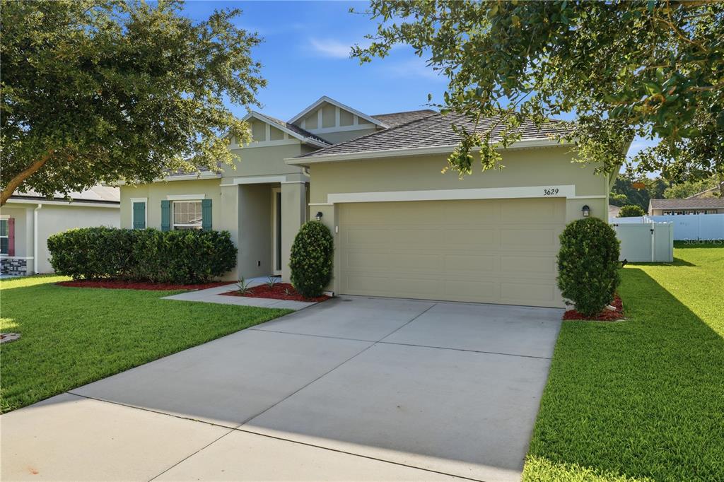 A single-story house with a beige stucco exterior, a two-car garage, and a green lawn — 3629 PELOCK DRIVE, APOPKA, FL