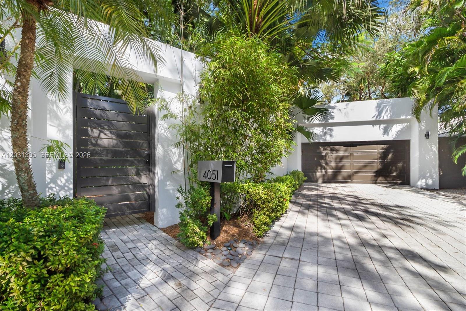 A modern home exterior features a paved driveway, a dark gate, and a mailbox — 4051 Ensenada Avenue, Miami FL 33133, MIAMI, FL