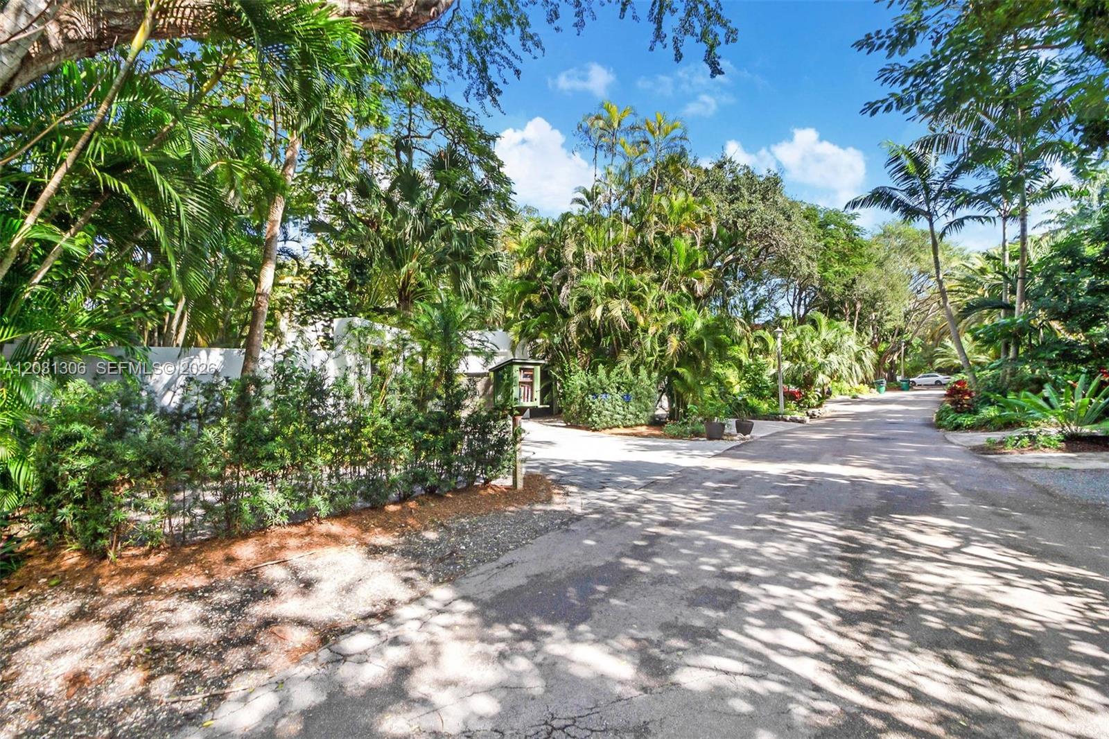 A paved driveway leads toward a house surrounded by lush tropical trees and foliage — 4051 Ensenada Avenue, Miami FL 33133, MIAMI, FL