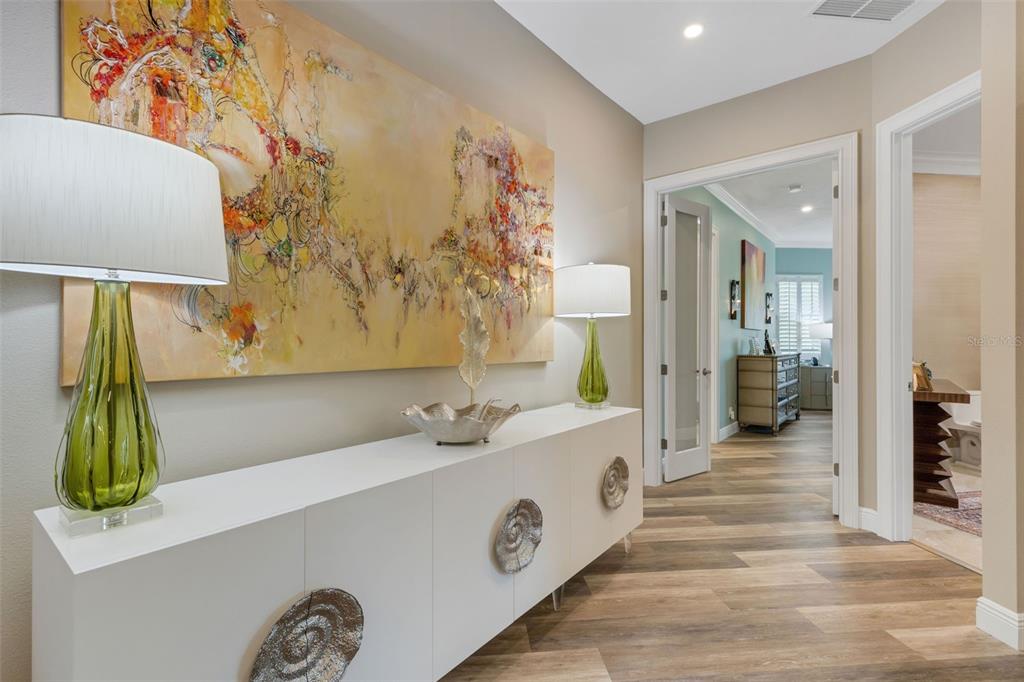 A hallway features a white console table, two green lamps, and a large abstract painting — 7732 DONALD ROSS ROAD W, SARASOTA, FL