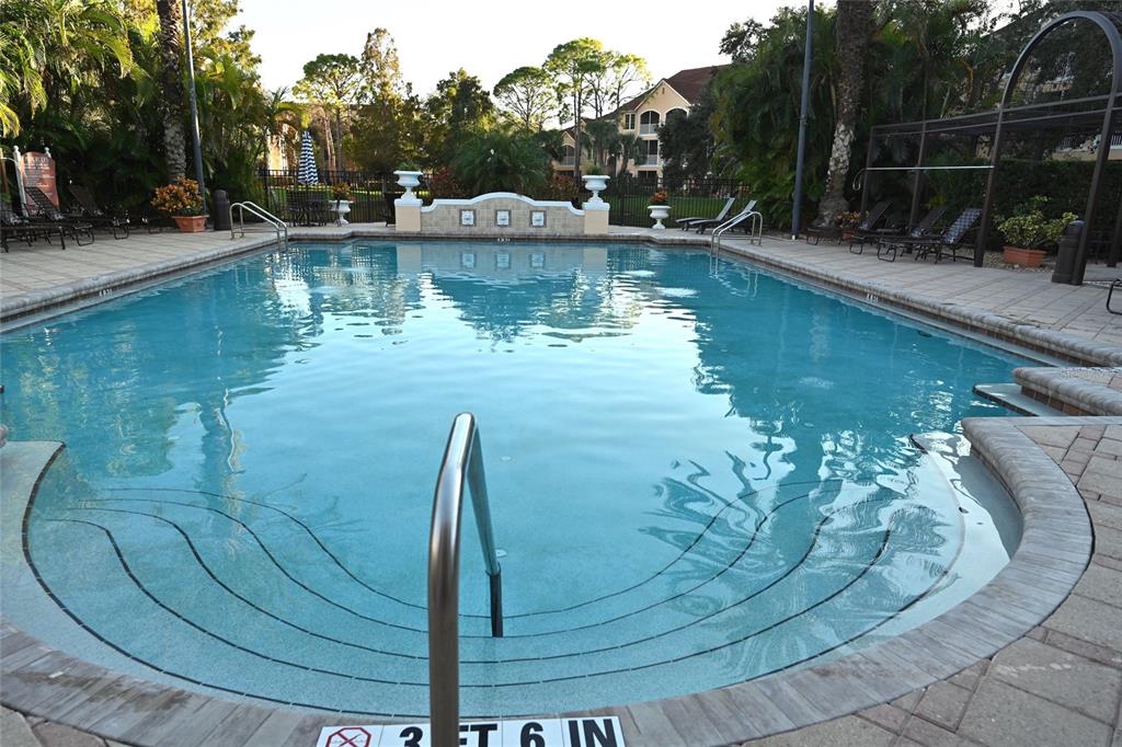 A rectangular swimming pool with entry steps and a metal handrail sits on a patio — 4178 CENTRAL SARASOTA PARKWAY UNIT 323, SARASOTA, FL