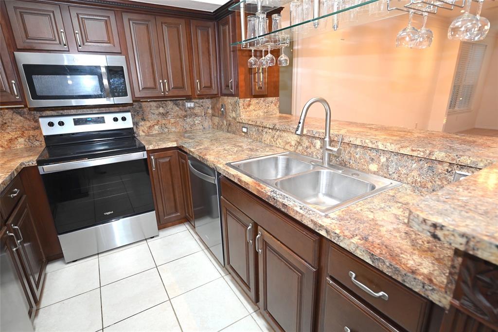 A kitchen features dark wood cabinets, granite countertops, stainless steel appliances, and a double sink — 4178 CENTRAL SARASOTA PARKWAY UNIT 323, SARASOTA, FL