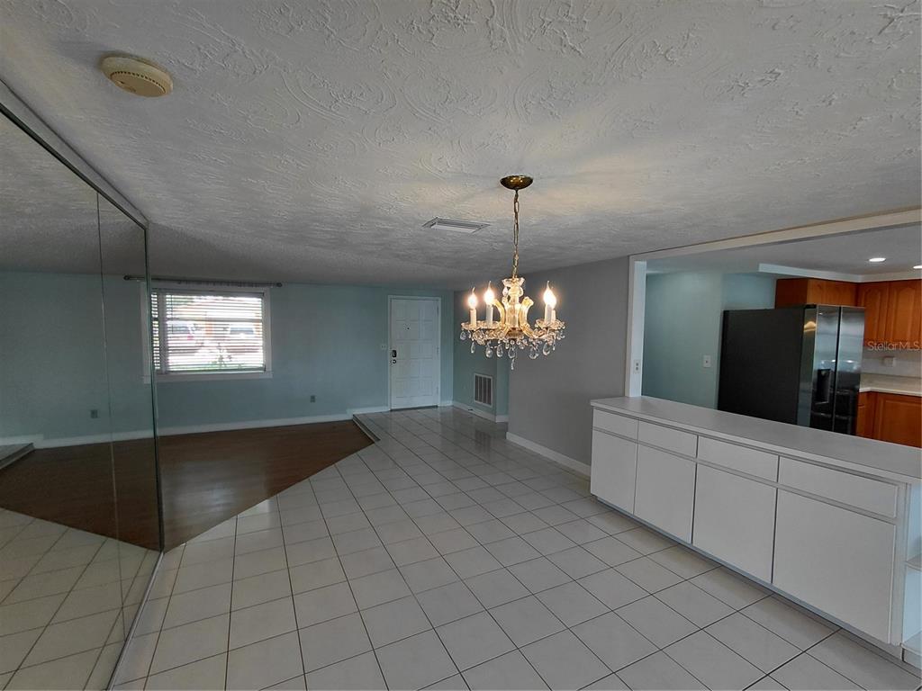A room with white tile flooring, a crystal chandelier, and a mirrored wall — 4113 STAR ISLAND DRIVE, HOLIDAY, FL