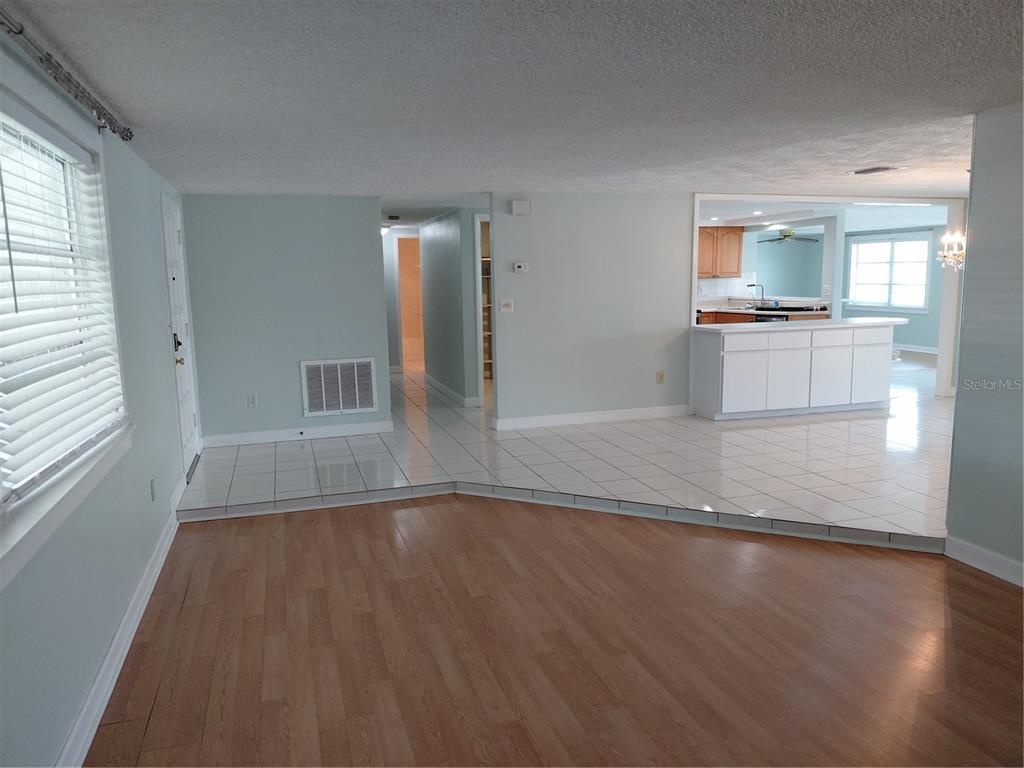A living room with wood-look flooring transitions to a tiled kitchen area with a breakfast bar — 4113 STAR ISLAND DRIVE, HOLIDAY, FL