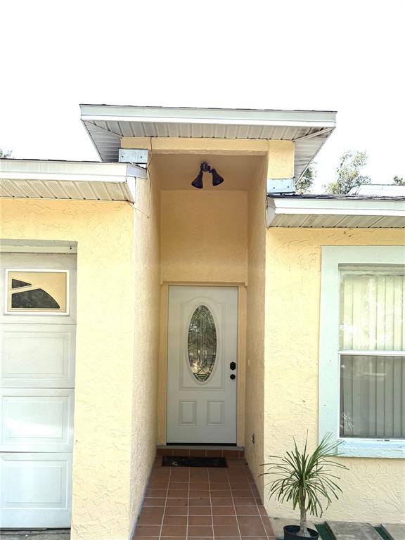 A yellow stucco house exterior features a recessed front entrance with a white door — 6308 N 22ND STREET, TAMPA, FL